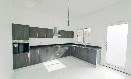 A luxury kitchen with white cabinets and stainless steel appliances in a 4BR Villa located in Al Shakhura.