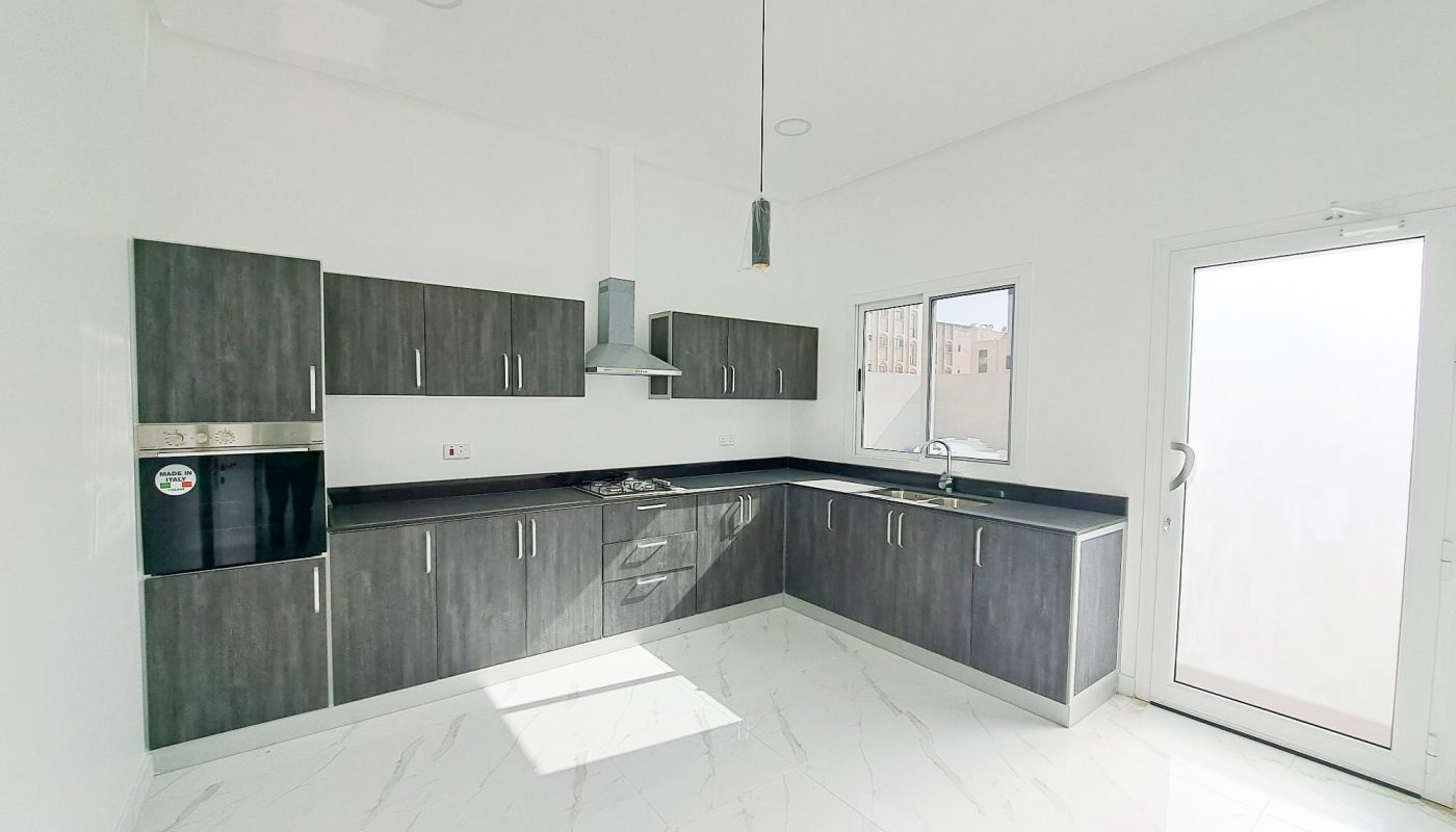 A luxury kitchen with white cabinets and stainless steel appliances in a 4BR Villa located in Al Shakhura.