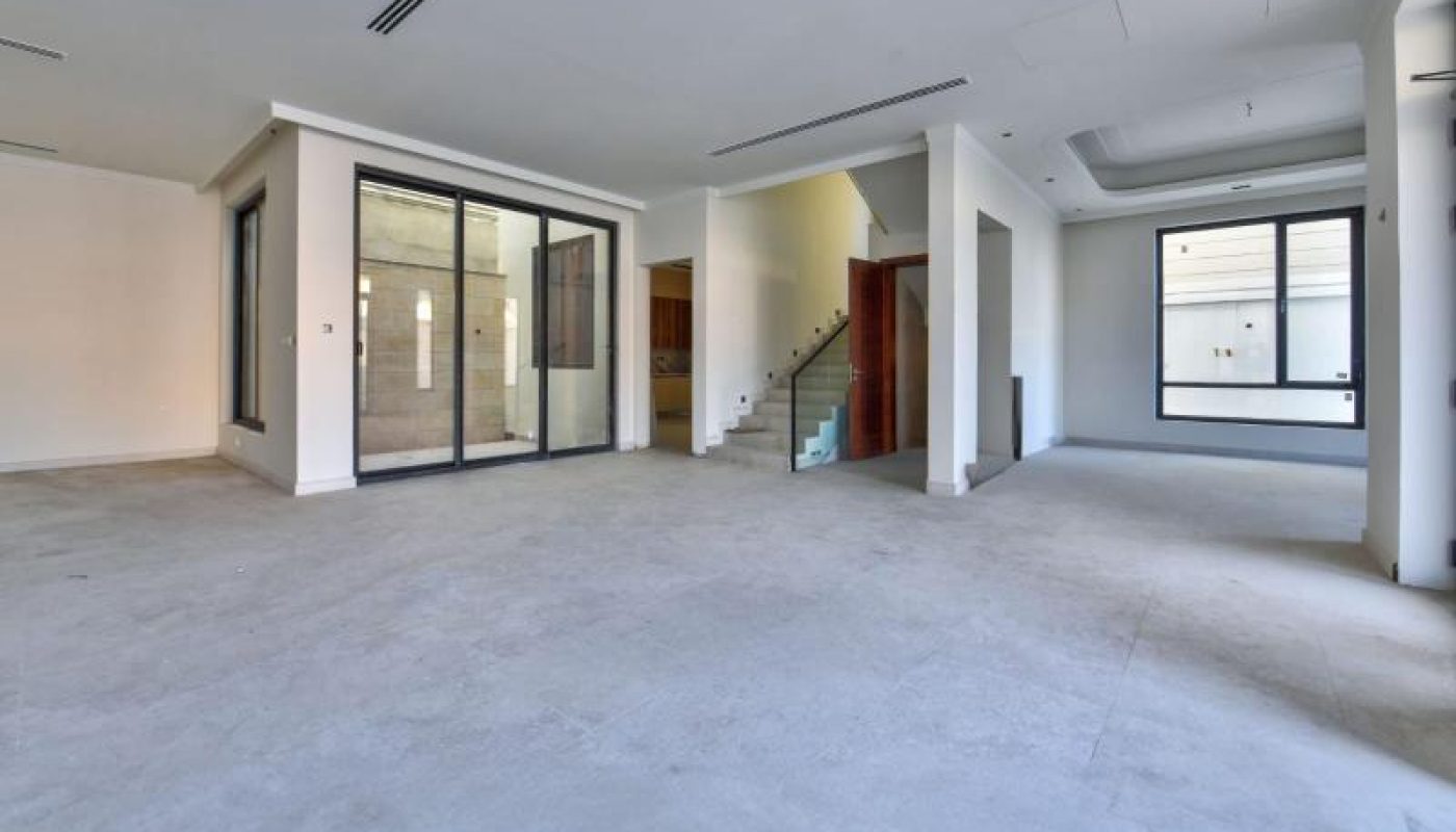 Spacious, empty modern interior with large windows, sliding glass doors, and a staircase leading to an upper floor.