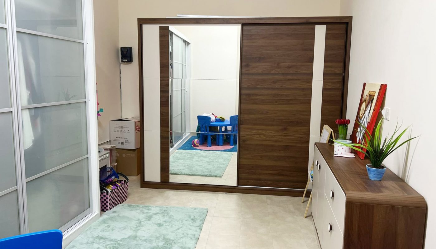 A cozy child's room with a blue chair and a mirror.