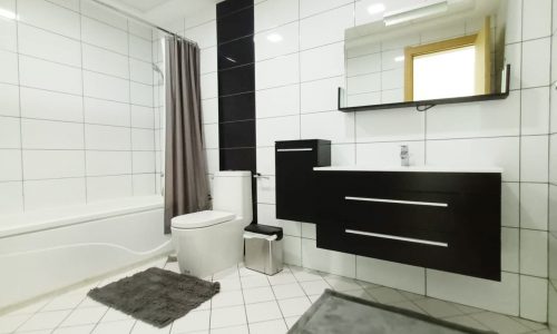 A luxurious apartment in Seef, with a chic white and black bathroom featuring a modern toilet and elegant sink.