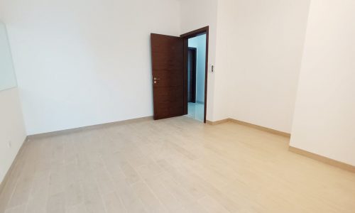 Spacious apartment with wooden floors and a door.