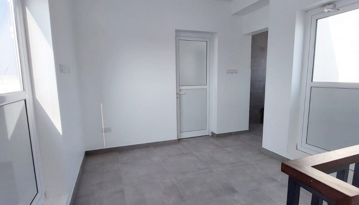 An empty room with white walls and a railing in a Great Villa for Sale in Durrat Al Muharraq.