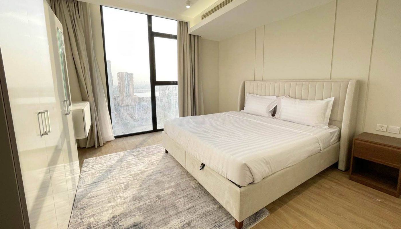 A bedroom with a large bed and an auto draft mechanism allowing for a view of the city.