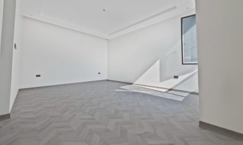 A large empty room with white walls and a wooden floor.