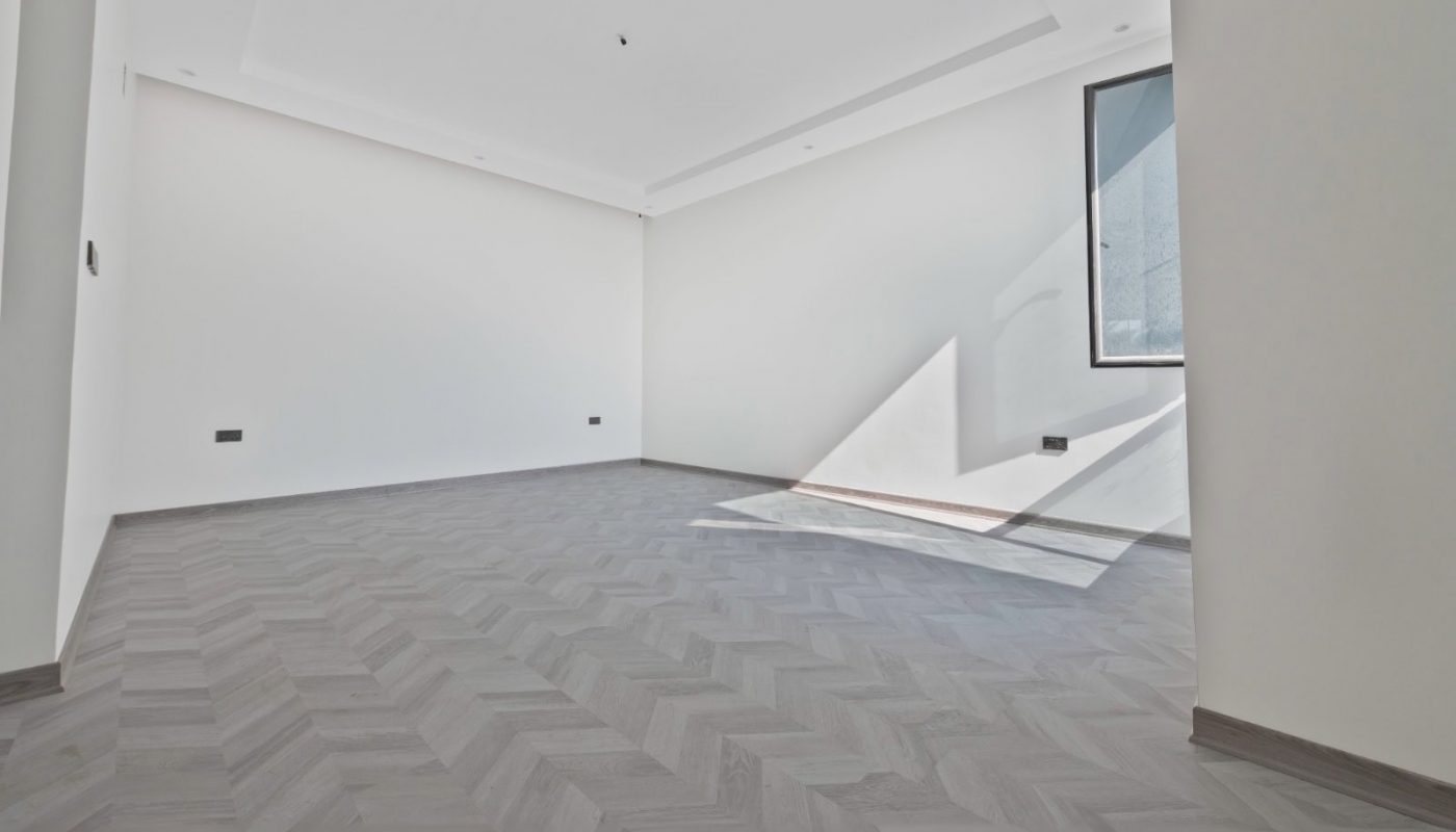 A large empty room with white walls and a wooden floor.