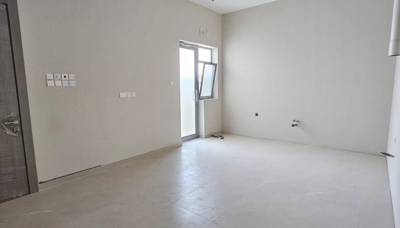 Empty room with light gray walls, a ceiling fan, and recessed lighting. There is a door and an open window on one wall. The floor is tiled, and electrical sockets are visible.