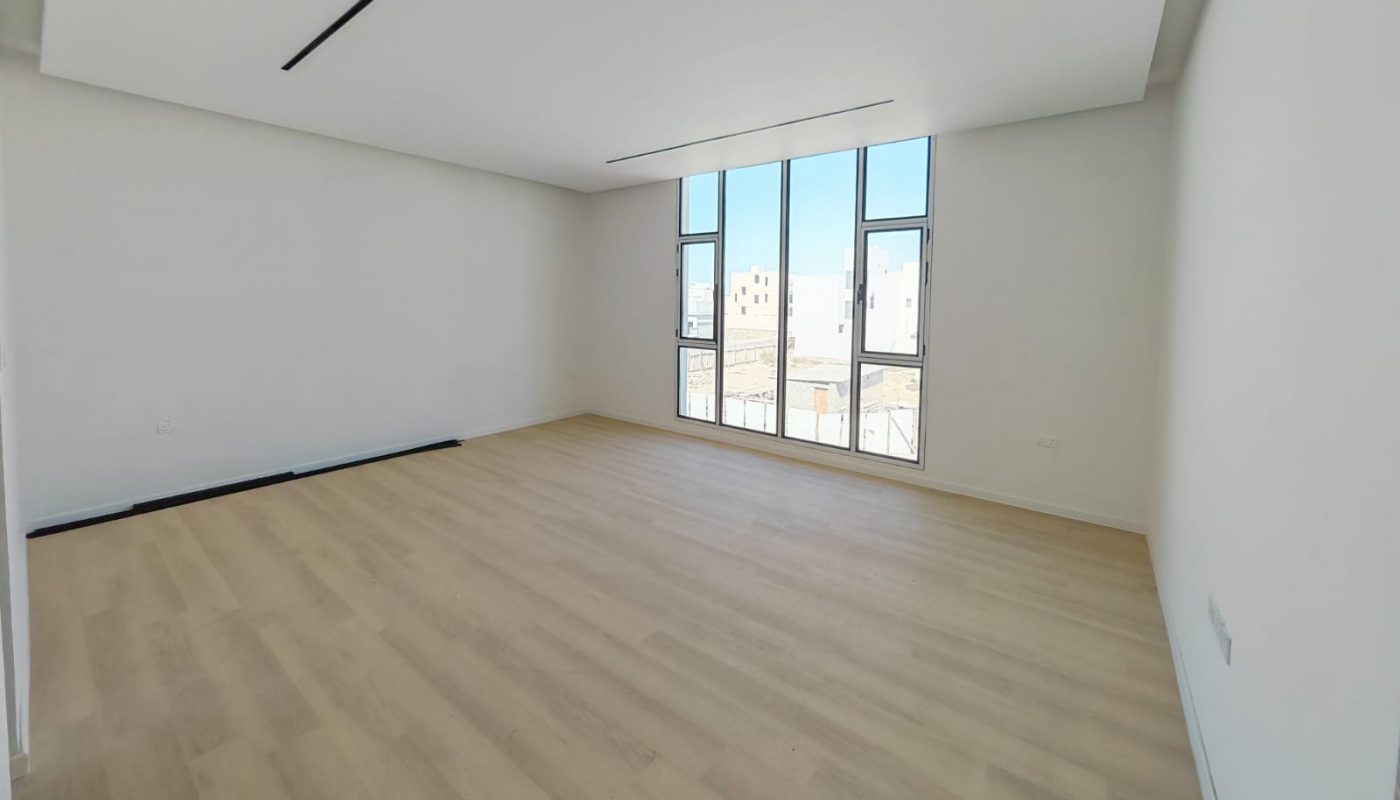 Empty room with light wood flooring, white walls, a recessed ceiling, and tall windows letting in natural light.