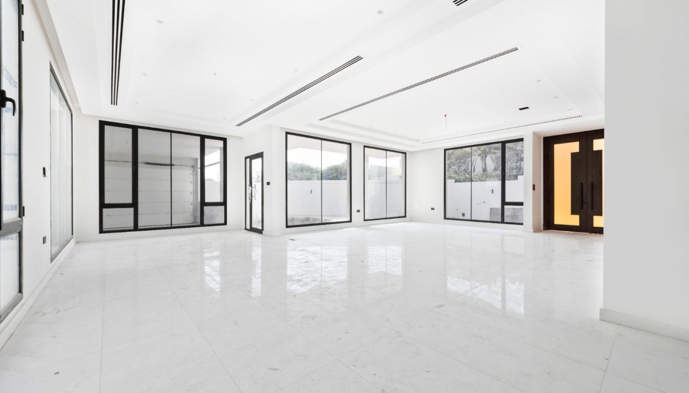 Spacious, empty modern room with large windows, white tile floors, and glass doors; natural light fills the space.