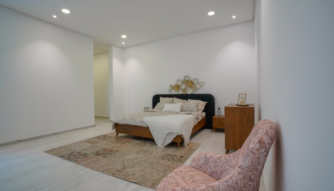 Spacious bedroom with a bed and a pink chair.