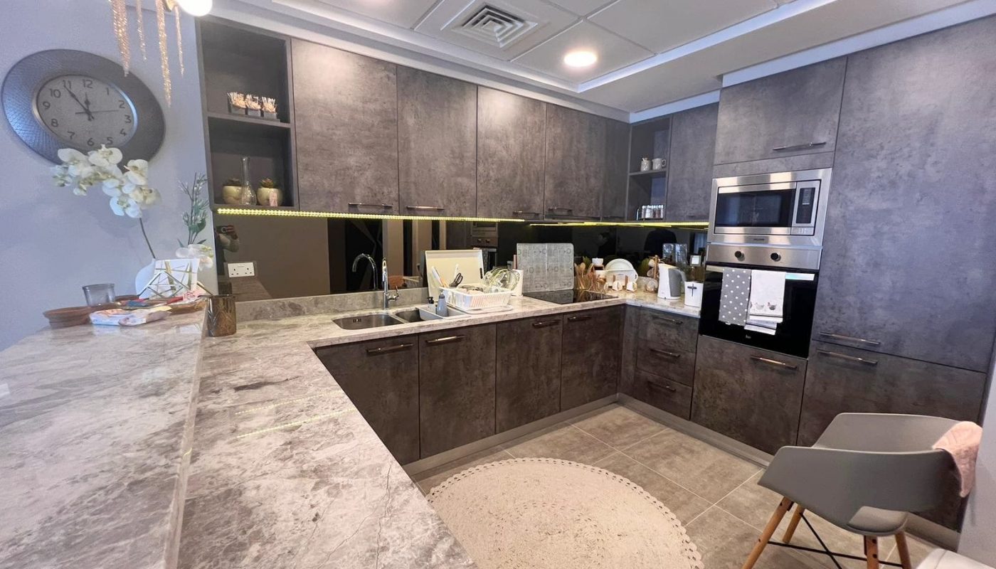 A luxurious kitchen with grey cabinets and marble counter tops.