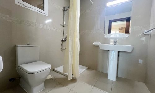 A bathroom with a toilet, sink, and shower in a semi-furnished 2-bedroom apartment in Hidd.