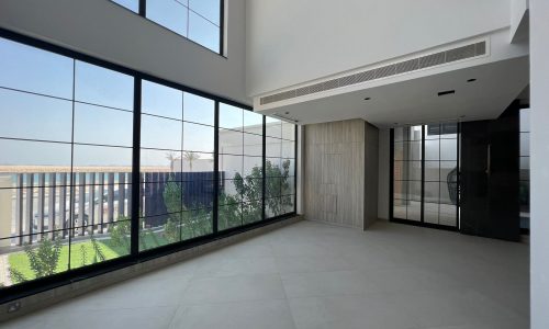 An empty room with large windows and a view of the city on Dilmunia Island.