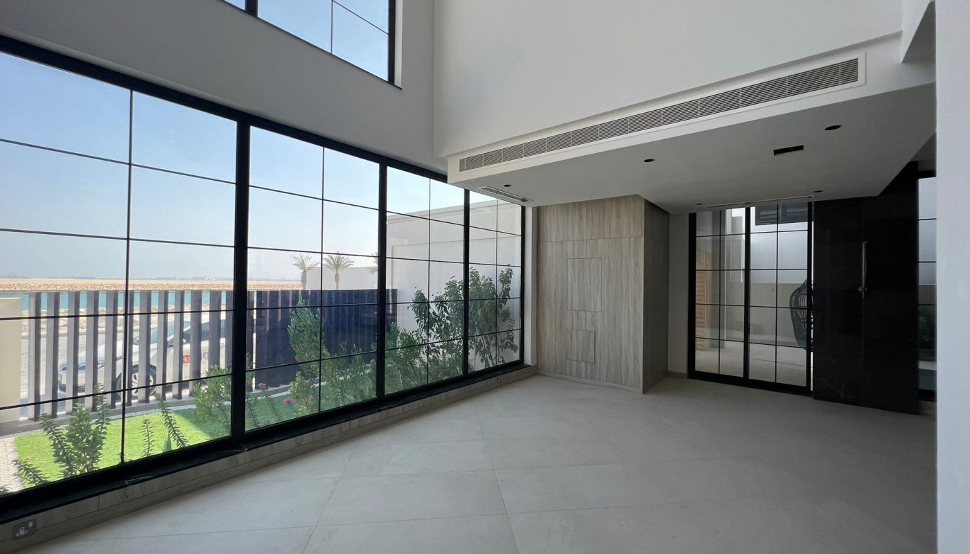 An empty room with large windows and a view of the city on Dilmunia Island.