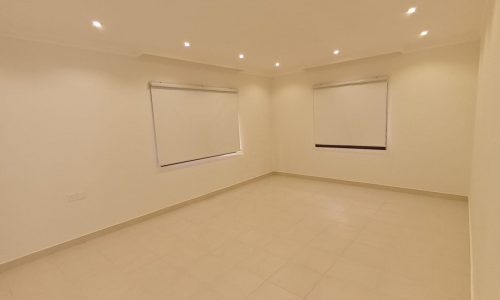 A luxurious room with spacious dimensions, featuring a white floor and tiled walls.