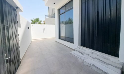 Modern villa for sale with large glass doors, a marble staircase, and dark metal gates in the peaceful area of Saar.