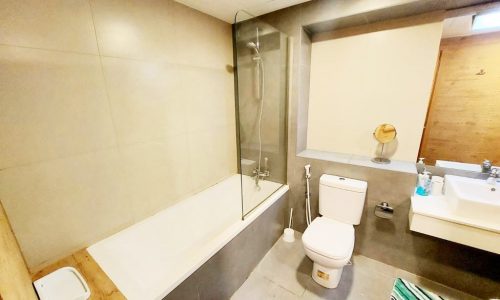 A modern bathroom with a toilet, sink and shower.