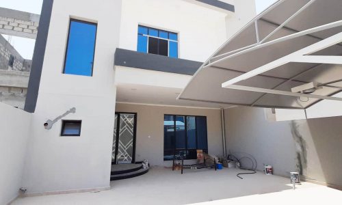 A luxurious house with a blue roof and white siding in Jid AL Haj.