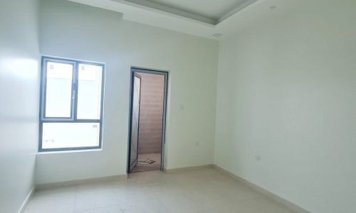 A stunning empty room with white walls and tile floors in a new villa for sale in Malkiyah.