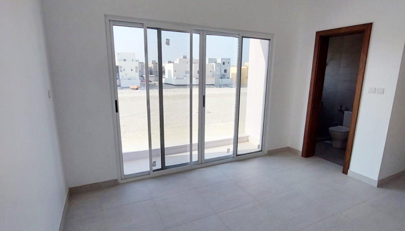 A spacious villa with sliding glass doors and a balcony, available for sale in Durrat Al Muharraq.