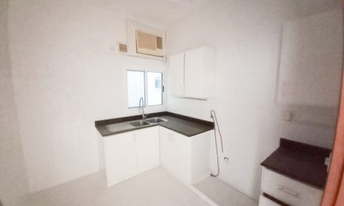 A view of a white kitchen with cabinets and a sink in an apartment.