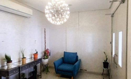 SF Modern 2BR Apartment for Rent in Mahooz features a room with a blue chair and a chandelier.