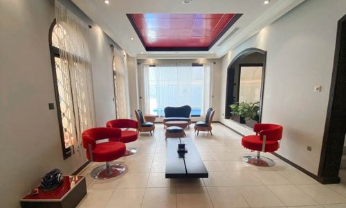 A breathtaking living room with red chairs and a tiled floor.