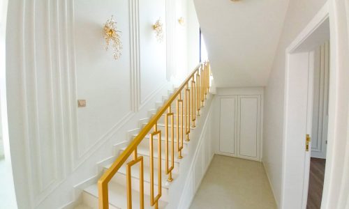 A luxurious white and gold stairway in a huge villa.