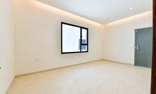 An empty room with white walls and a window in modern villas for sale.