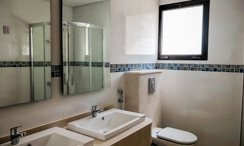 A bright and spacious bathroom with two sinks and a window.