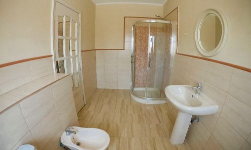 A luxury villa with a bathroom featuring a toilet, sink, and shower.