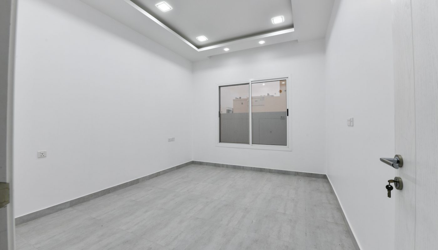 A luxurious apartment for sale near St. Christopher's School, featuring an empty room with white walls and wooden floors.