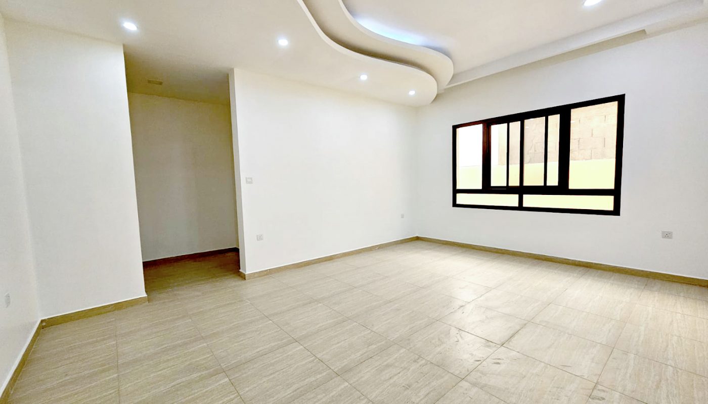 Empty room with beige tiled floors, white walls, a large window, and a unique recessed ceiling with built-in spotlights.