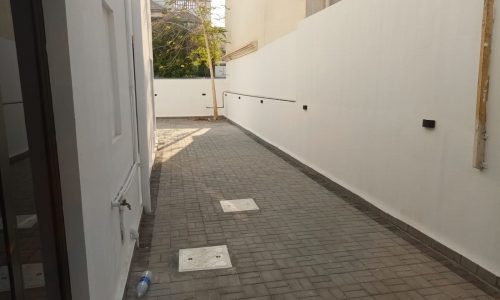 A small alleyway with a white wall leading to a luxurious door.