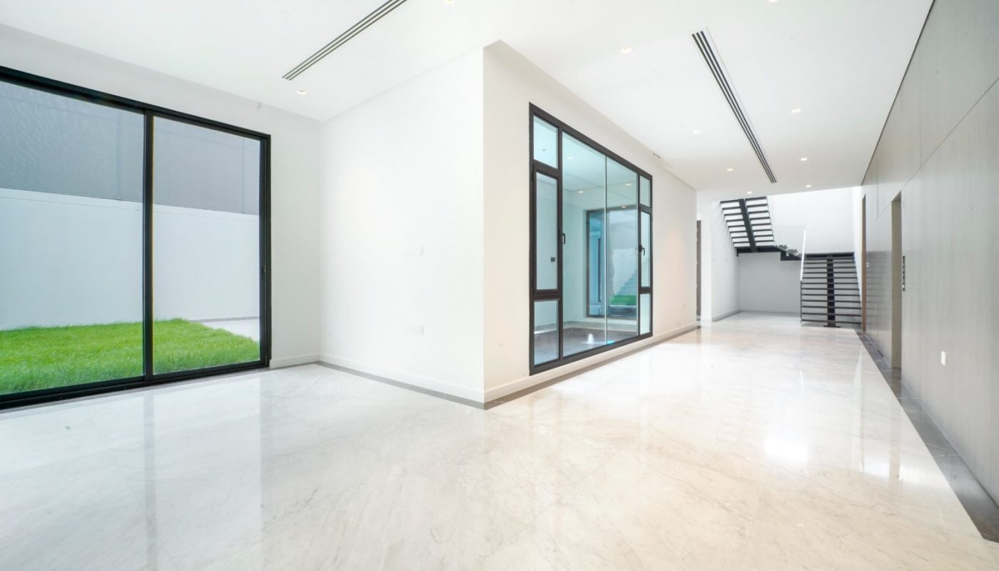 An exceptional white hallway with glass doors and a grassy area.