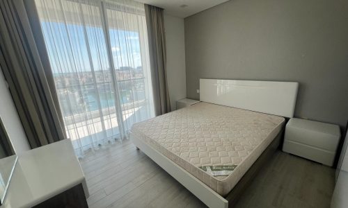 A bedroom with a bed and a view of the ocean.