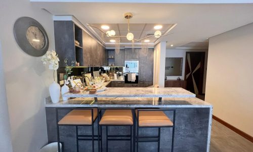 A luxurious kitchen with bar stools and a clock.