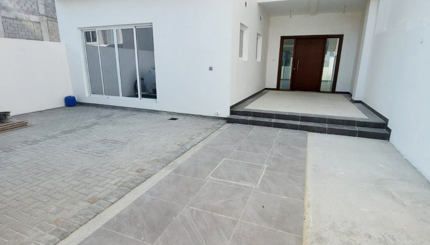 A white villa with a driveway and a door.