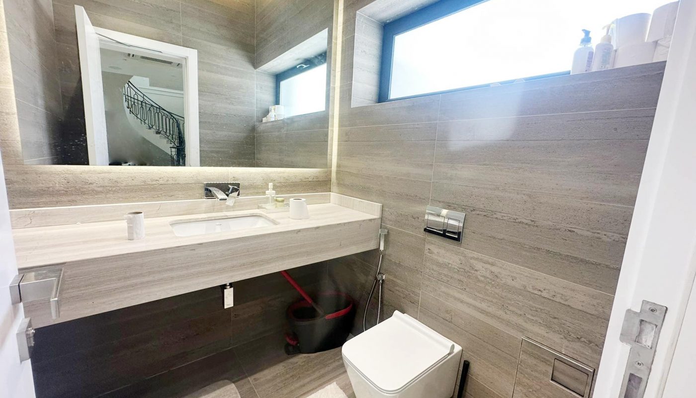 A modern villa in Hamala featuring a bathroom with a toilet, sink, and mirror.