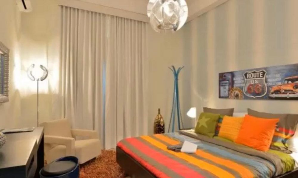 An amazing bedroom with a colorful bed spread and a lamp.