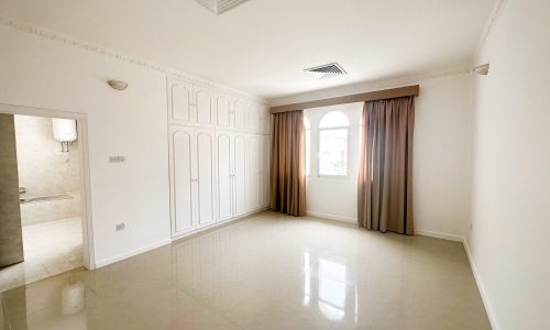 A spacious villa with three bedrooms available for rent, featuring an empty room with white walls and a ceiling fan.