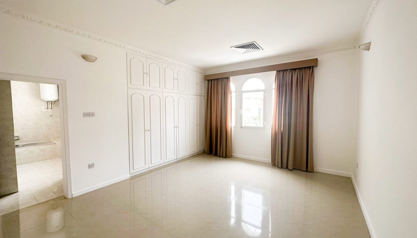 A spacious villa with three bedrooms available for rent, featuring an empty room with white walls and a ceiling fan.