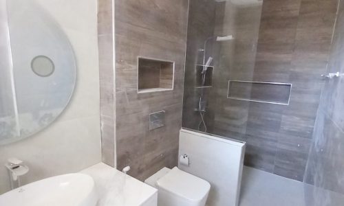 A mesmerizing bathroom with a toilet, sink, and shower in a 5BR Villa for Sale in Tubli.