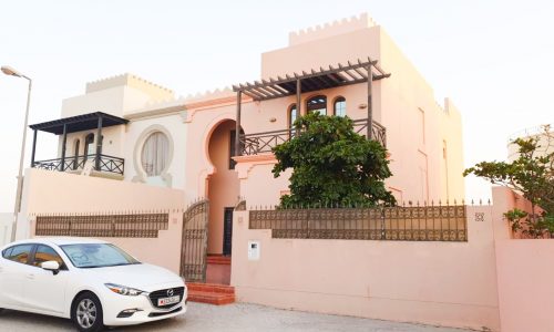 An amazing pink car is parked in front of a pink house.