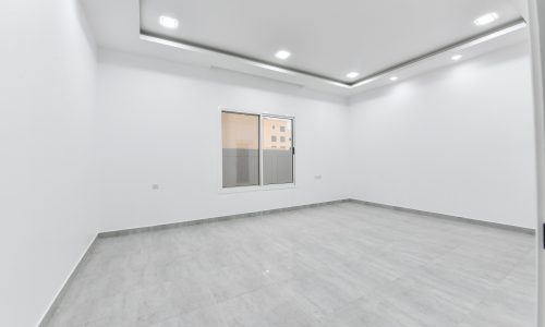 A luxurious apartment with white walls and a window, available for sale.