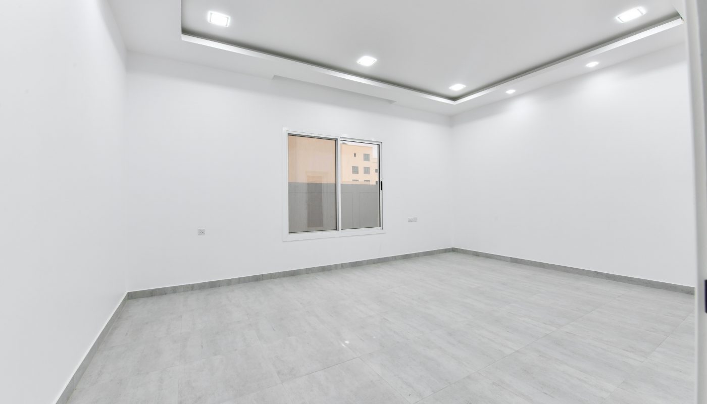 A luxurious apartment with white walls and a window, available for sale.