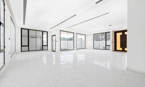 A large empty room with white tile floors and large windows.