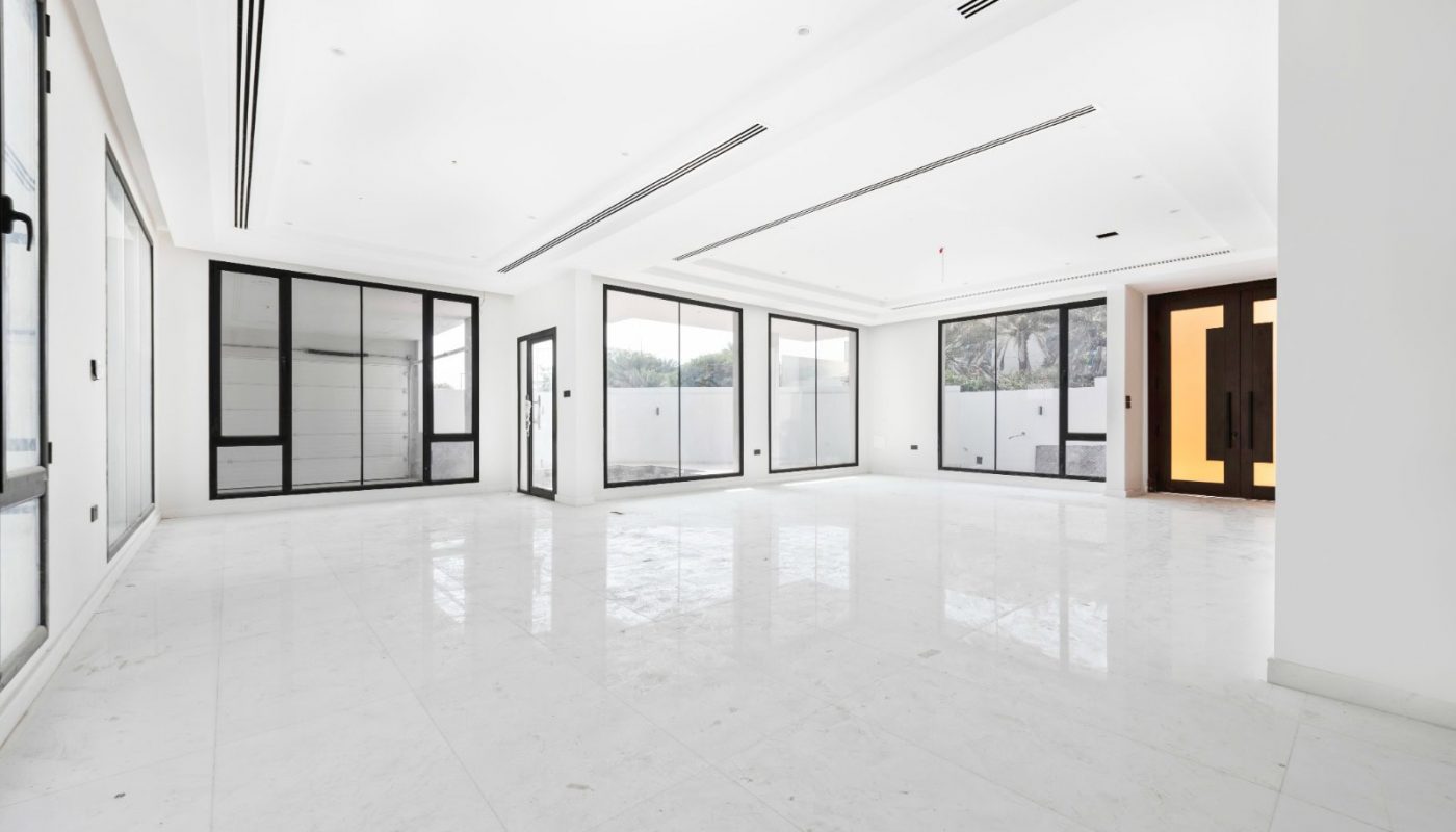 A large empty room with white tile floors and large windows.