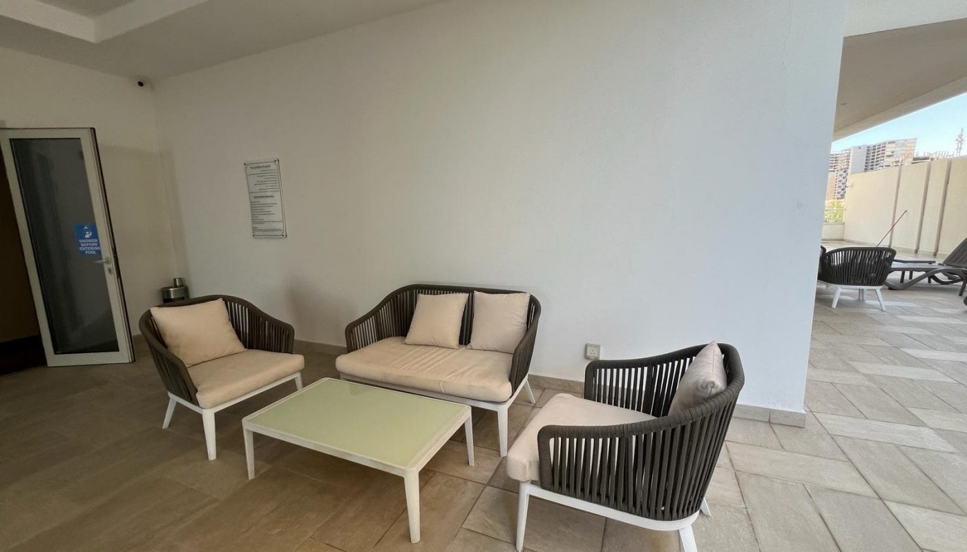 An Amwaj flat for rent, featuring a living room with wicker furniture and a coffee table.
