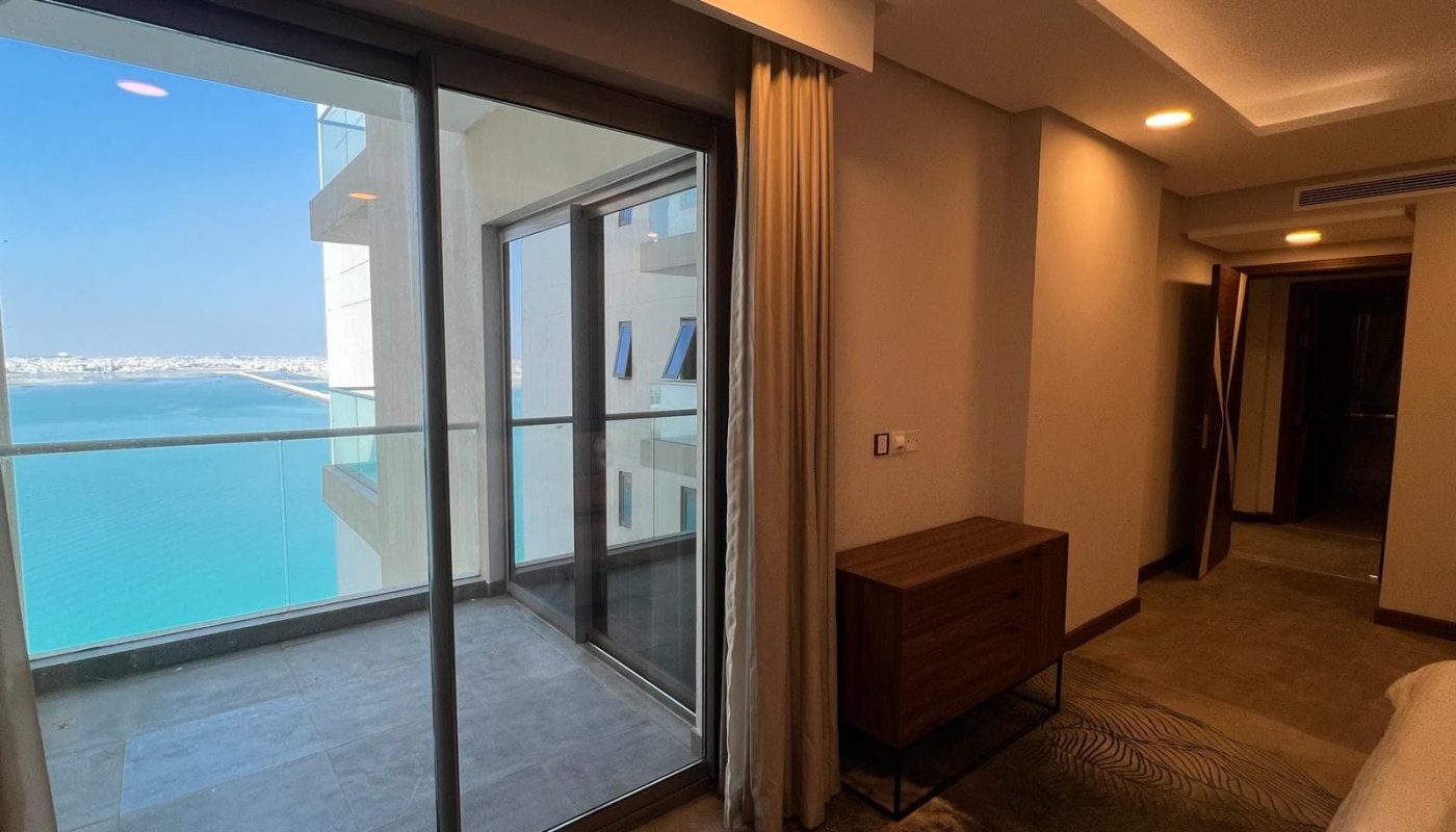 A luxury bedroom with a balcony overlooking the ocean.